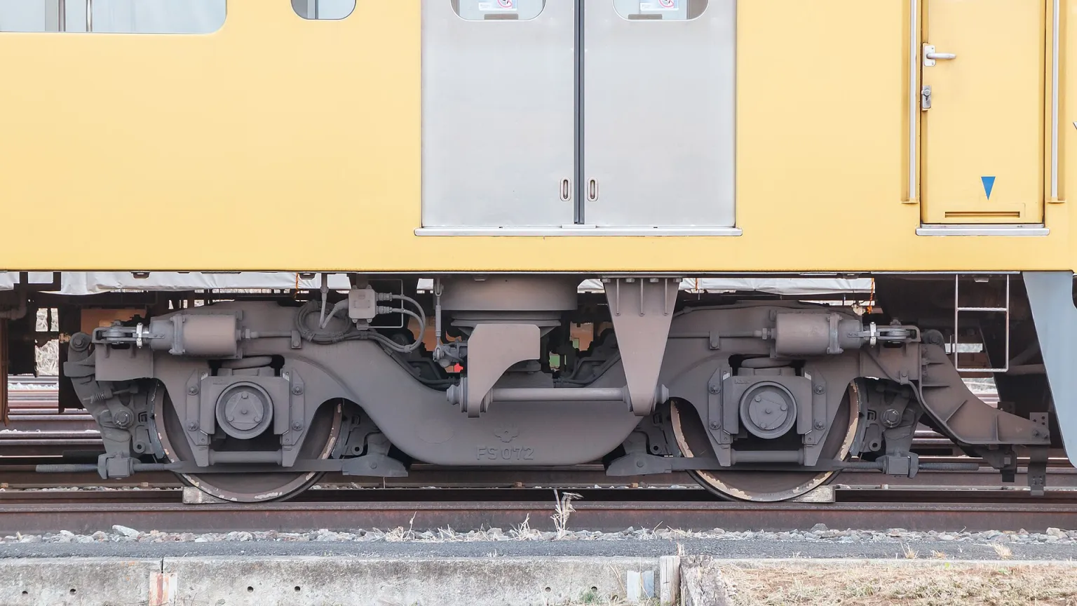 Close-up of a modern passenger-train bogie and its wheelsets beneath a railcar